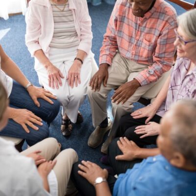 Grupa seniorów siedzi w kręgu podczas sesji terapii współuzależnienia.
