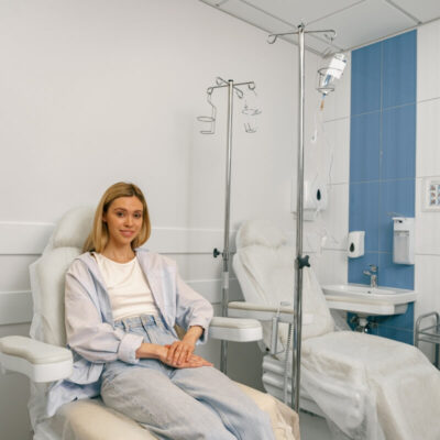Kobieta siedzi w nowoczesnym gabinecie, gdzie pacjenci otrzymują wlewy dożylne.
