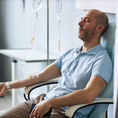 Mężczyzna siedzi na krześle, otrzymując wlewy dożylne.